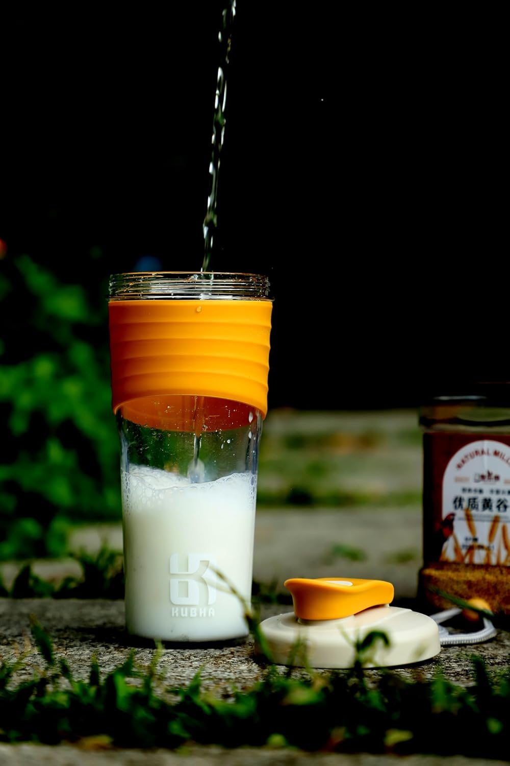 Glass tumbler with orange lid being filled with a white powdery substance outdoors.