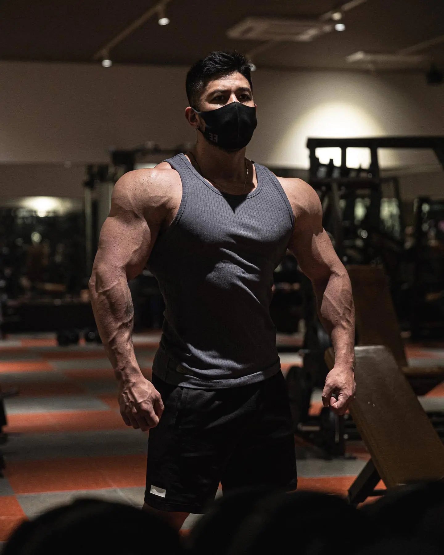 Muscular man in a gym wearing a face mask