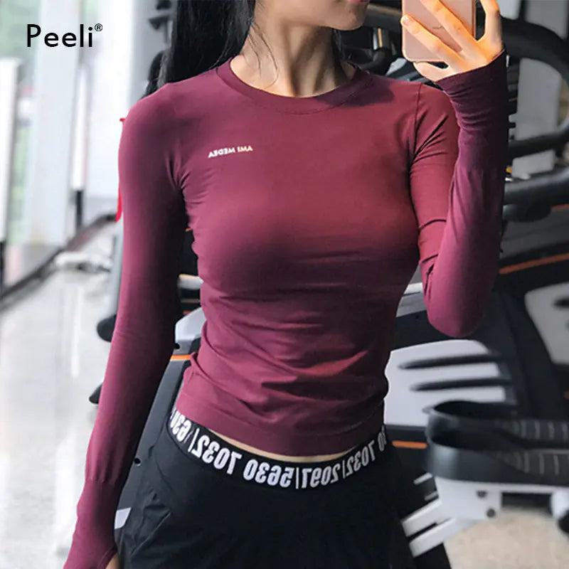 Person wearing a maroon long-sleeve athletic top with visible branding in an indoor setting.