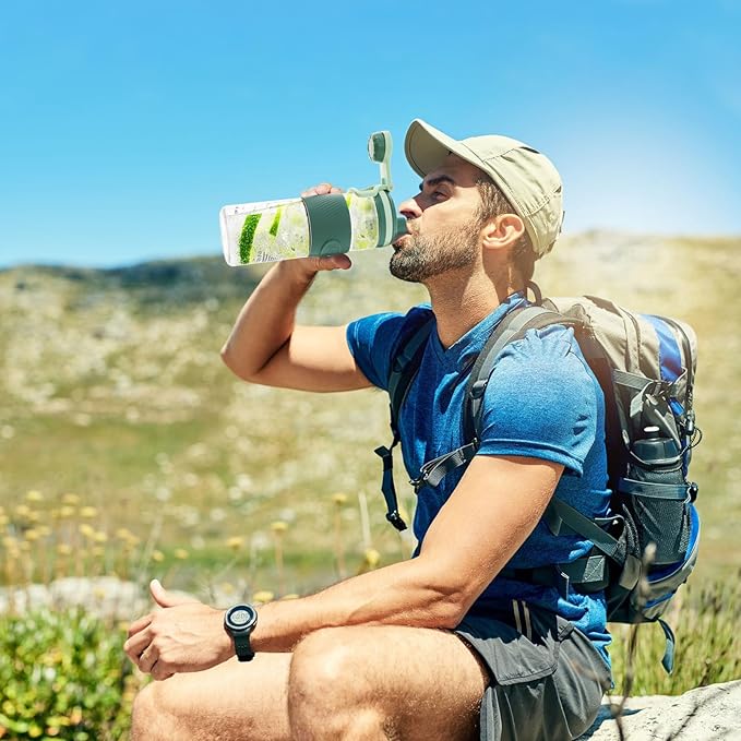 Man in outdoor setting drinking from a water bottle with a scenic background