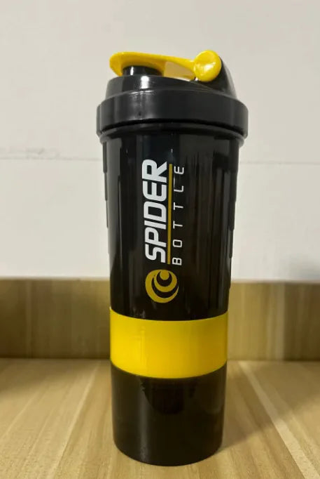 Black and yellow Shaker Bottle on a wooden surface with a white wall background