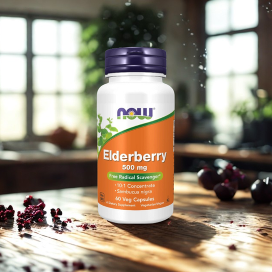 Bottle of NOW Elderberry 500 mg supplement on a wooden surface with blurred indoor background