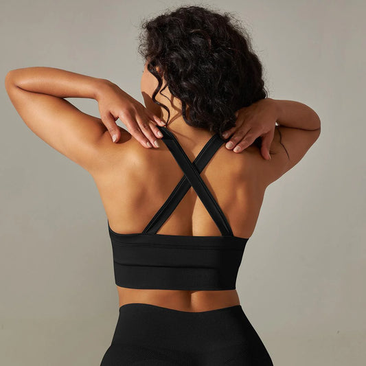 Person wearing a black sports bra with criss-cross straps on a neutral background