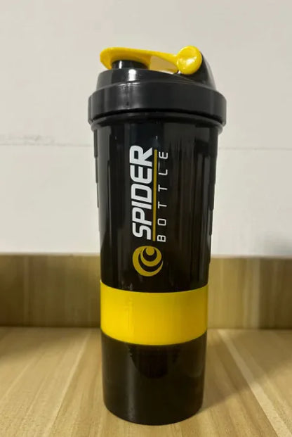 Black and yellow Shaker Bottle on a wooden surface with a white wall background